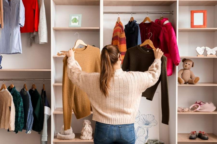 A woman organizing her wardrobe and choosing pieces for a sustainable capsule collection.