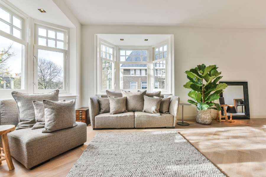 A beautifully arranged small living room with a comfortable beige sofa, large windows, and a soft neutral rug.