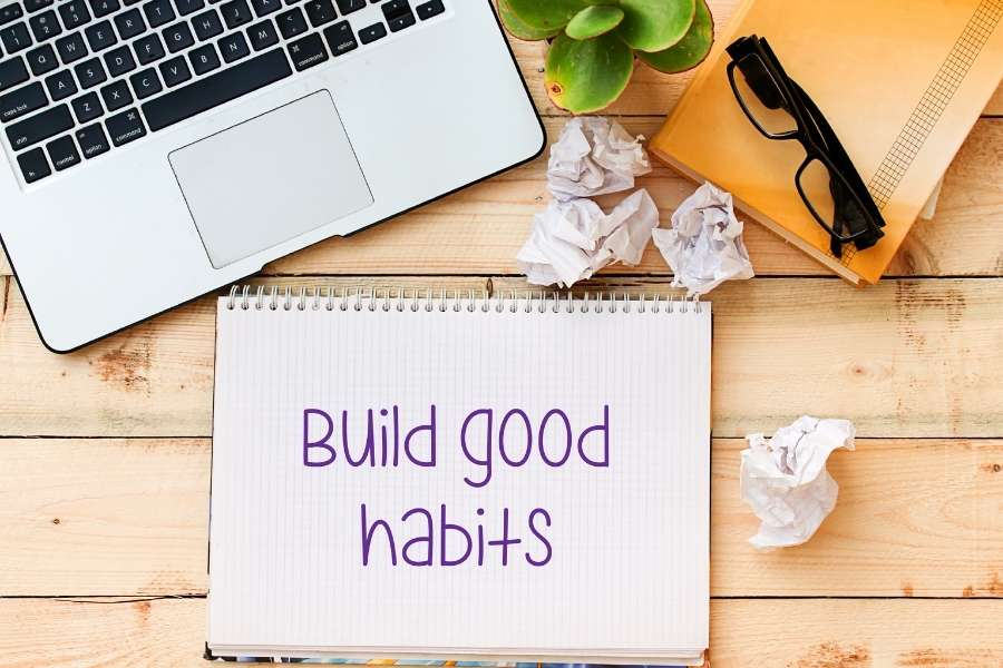 A notebook with the text Build good habits displayed on a wooden desk, representing daily habits.
