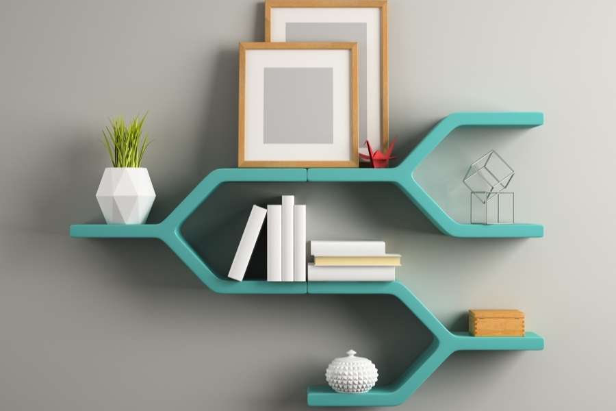 A unique and modern turquoise branch-shaped custom floating wall shelf mounted on a gray wall, showcasing books and decorative items.