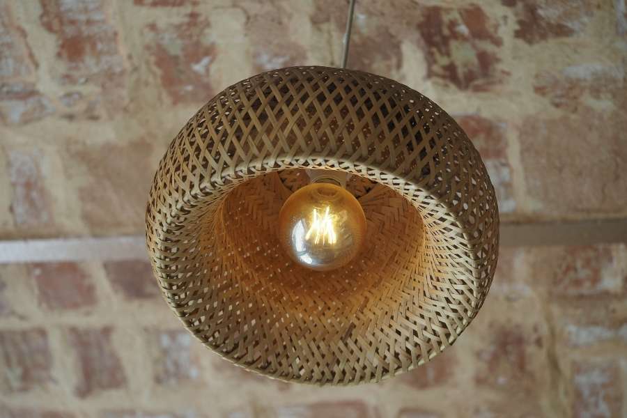 Woven rattan industrial light fixtures hanging against a rustic brick wall.