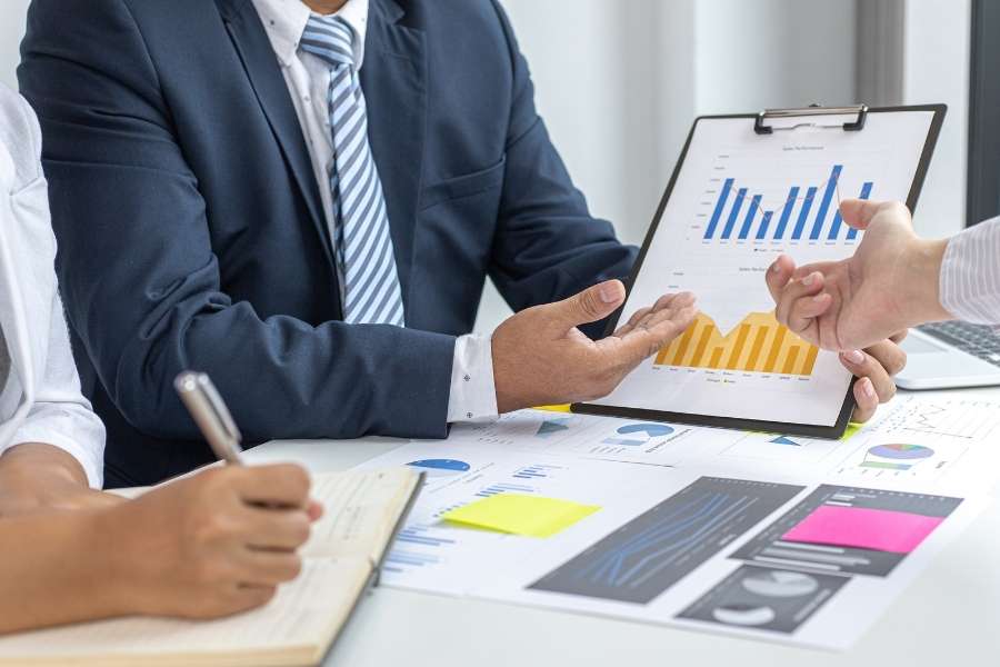 Professionals analyzing financial performance charts on a clipboard to optimize the management of Construction Businesses.